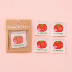 Verpackung neben vier ausgelegten Tomato-Pin-Cushion-Weblabels.