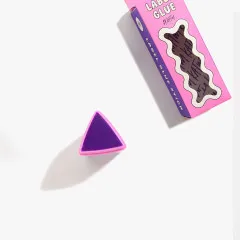 Flatlay-Aufnahme von oben: Ecke der Verpackung mit Wellenfenster neben der abgenommenen Kappe und der freigelegten violetten Klebemasse.