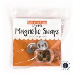 Vorderseite der Verpackung 'Magnetic Snaps' von Sassafras Lane Designs mit Aufschrift '2 sets of orange snaps'.
