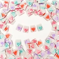 Je ein Bonbonherz-Weblabel mit „Hand Made", „With Love", „For You" und „For Me" nebeneinander angeordnet, umgeben von weiteren verstreuten Labels.