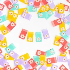 Je ein Gänseblümchen-Weblabel in Koralle, Gelb, Mint und Lavendel zu einem Herz angeordnet, umgeben von weiteren verstreuten Labels.