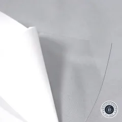 Nahaufnahme der transparenten Vinylfolie, an der Ecke über grauem Stoff hochgeklappt.