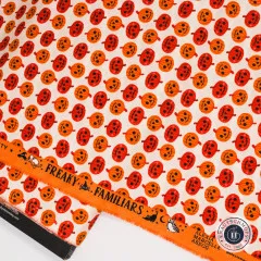 Stoffkante mit Aufdruck Freaky Familiars und Kürbismotiven in Orange und Rot auf cremefarbenem Grund