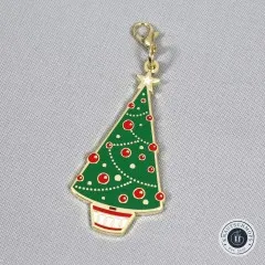 Nahaufnahme des Anhängers in Form eines grünen Weihnachtsbaums mit roten Kugeln und Stern.