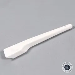 Der weiße Finger Presser freiliegend auf grauem Stoff, diagonal fotografiert.