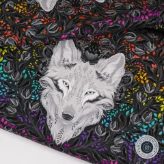 Extreme Nahaufnahme eines Wolfsgesichts mit fein gezeichnetem Fell zwischen dunklen Blättern.