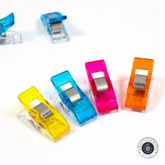 Wonder Clips in Gelb, Blau, Pink und Orange schräg von vorn mit sichtbarem Metallbügel