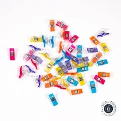 Bunte Clover Wonder Clips in Pink, Blau, Orange, Gelb und Lila lose auf weißem Untergrund