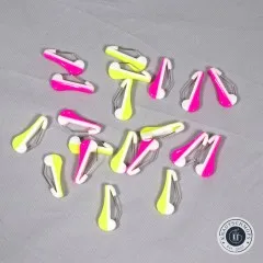 Mehrere Wonder Pins in Pink und Gelb lose auf grauem Stoff verteilt