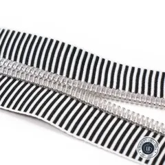 Nahaufnahme der geöffneten Zahnreihe des Reißverschlussbands Black Stripe mit silbern glänzenden Zähnen in Nickel-Finish.
