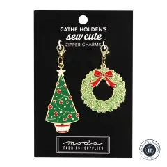 Zwei goldene Emaille-Anhänger von Cathe Holden: ein geschmückter Weihnachtsbaum und ein Türkranz mit roter Schleife, auf Verpackungskarte.