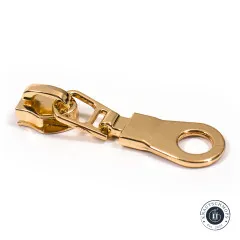 Makroaufnahme eines einzelnen goldfarbenen Zipper-Pulls mit Blick auf Schieber und Donut-Loch-Zuglasche.