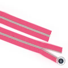 Zwei parallel liegende offene Enden des rot-hellrosa gestreiften Reißverschlussbands Red Stripe mit Nickel-Zähnen.