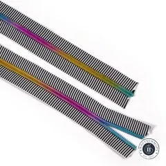 Zwei diagonal ausgelegte Längen des schwarz-weiß gestreiften Reißverschlussbandes mit Regenbogen-Zahnreihe auf weißem Hintergrund.
