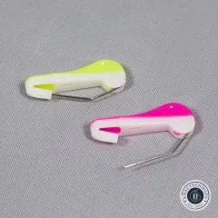 Nahaufnahme von zwei geöffneten Wonder Pins in Gelb und Pink auf grauem Stoff